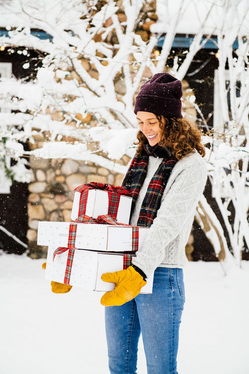 Load image into Gallery viewer, A woman in sweater and scarf holding boxes wrapped in ribbon
