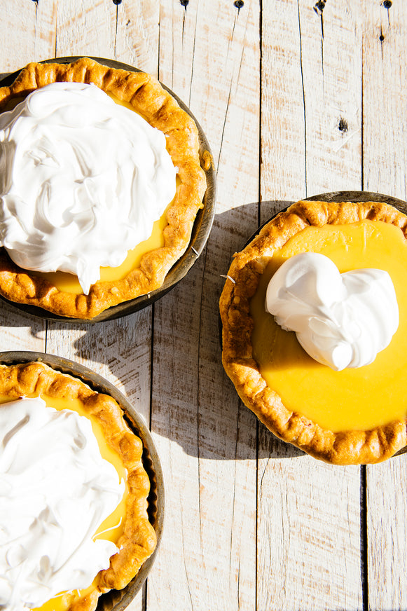 Small pies filled with lemon curd and topped with fresh whipped cream