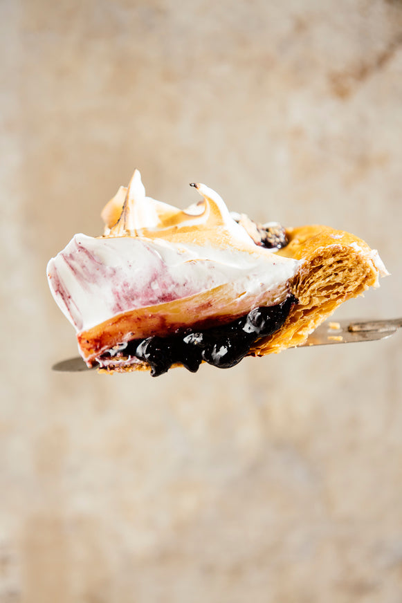 A slice of lemon blueberry pie topped with fresh whipped cream. 