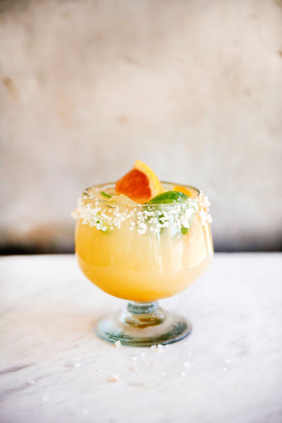 Margarita cocktail in a glass with salted rim and fresh citrus on a marble surface