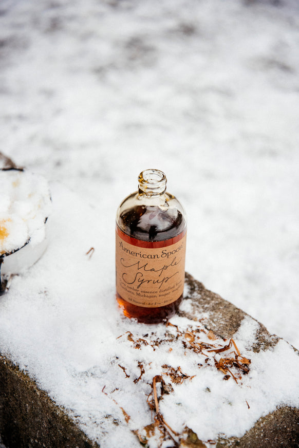 a jar of 8.5 oz maple syrup on a snowy fence