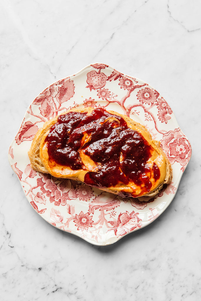 a slice of toast topped with peanut butter and preserves