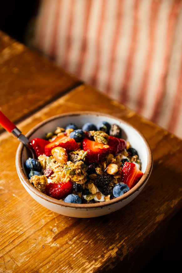 A bowl of granola with berries and honey