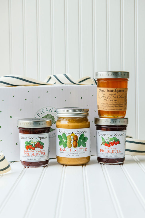 A gift box with peanut butter, fruit preserves and honey