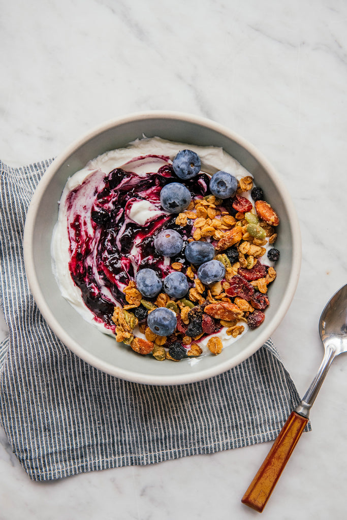 A bowl of yogurt topped with preserves, blueberries and granola