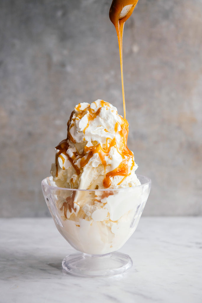 a bowl of vanilla ice cream and whipped cream topped with caramel
