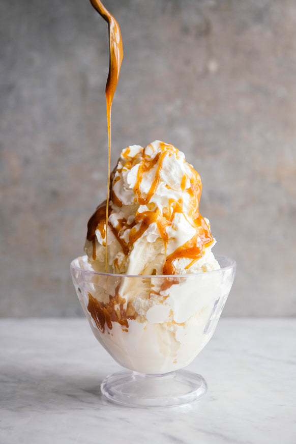 a bowl of vanilla ice cream and whipped cream topped with caramel