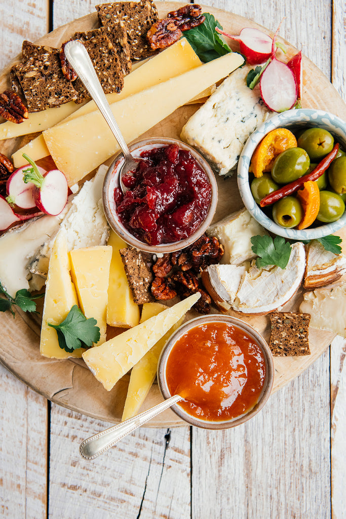 a charcuterie tray of cheeses, crackers, olives, candied pecans and various preserves and jams