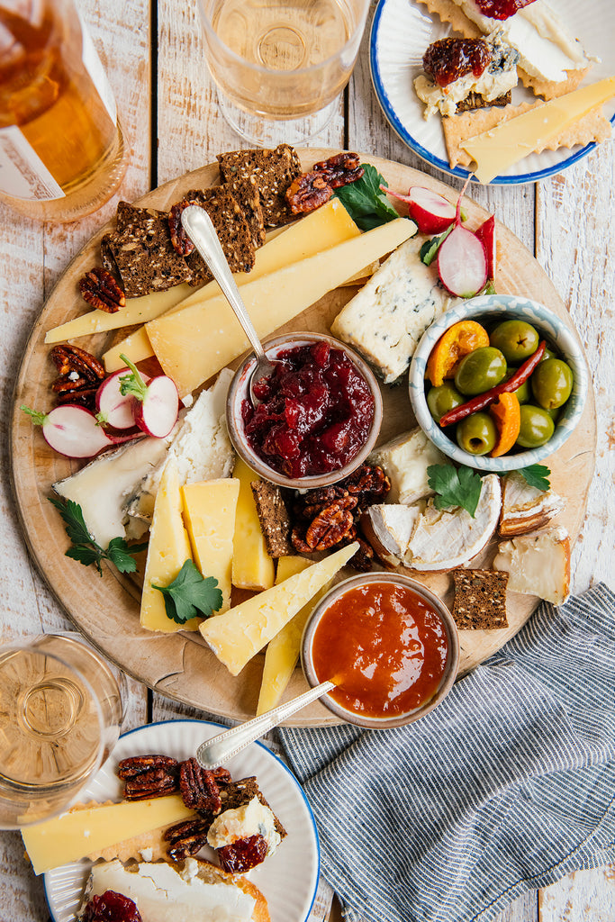a charcuterie tray of cheeses, crackers, olives, candied pecans and various preserves and jams