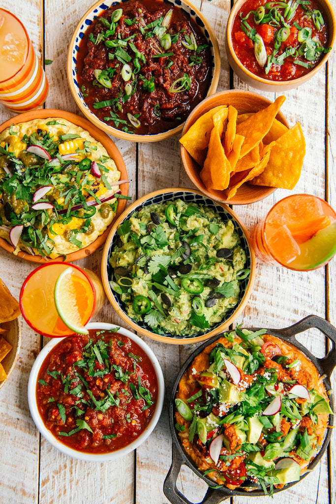 A colorful arrangement of dips, salsas, chips and margaritas