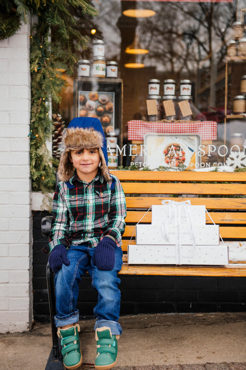 Load image into Gallery viewer, Young Boy on a bench in front of a store window with holiday decorations.
