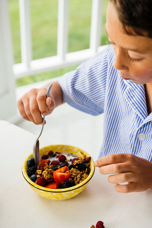 Load image into Gallery viewer, Young boy on porch, eating Maple Granola by the spoonful with milk

