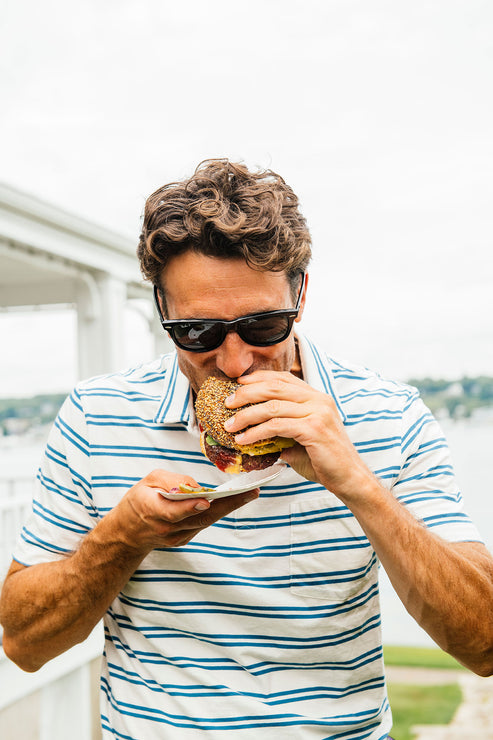 Load image into Gallery viewer, Man enjoying a classic cheeseburger with American Spoon condiments. 
