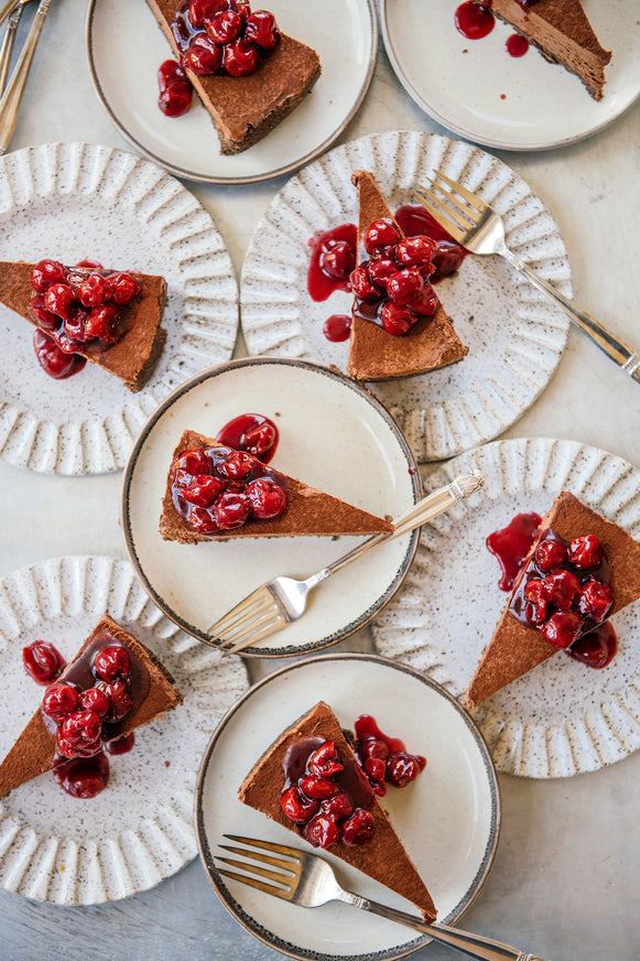 Slices of Chocolate Cheesecake with Christmas Cherries spooned on top.