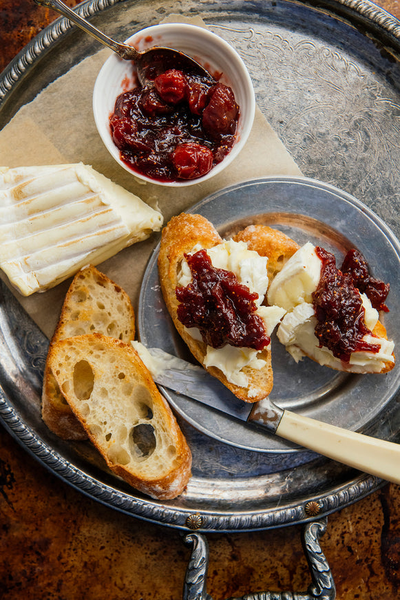 a tray of baguette slices topped with brie and holiday jam