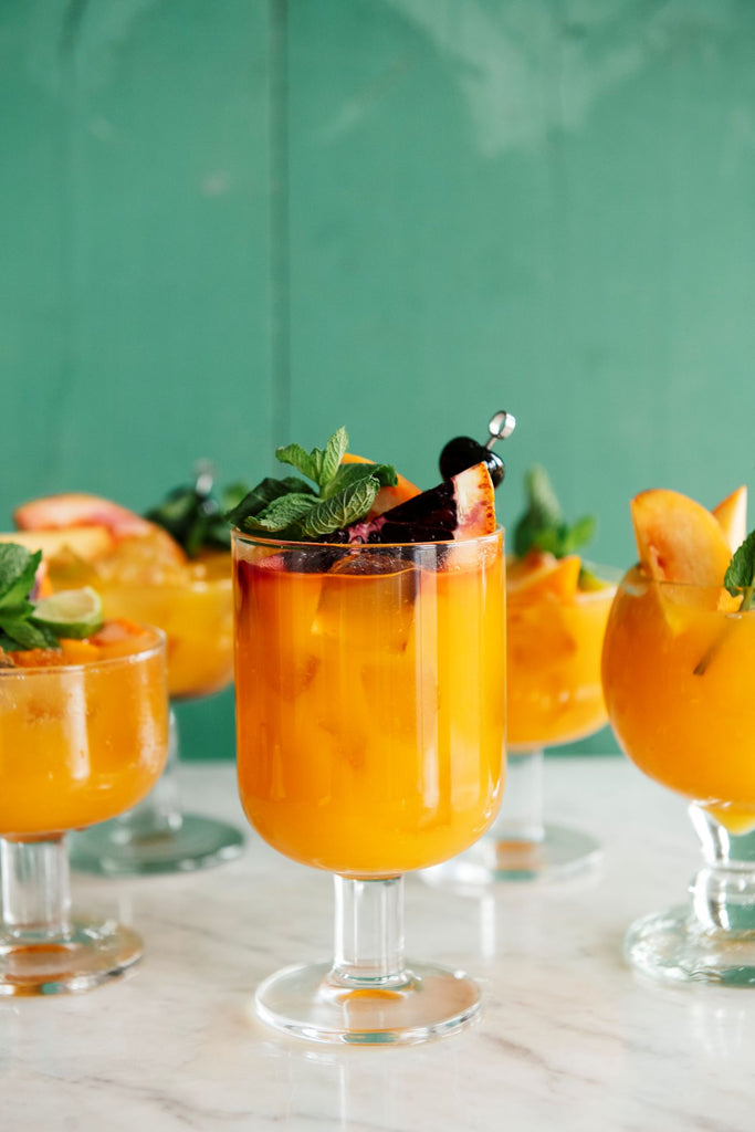 glasses of peach punch with fresh fruit garnishes