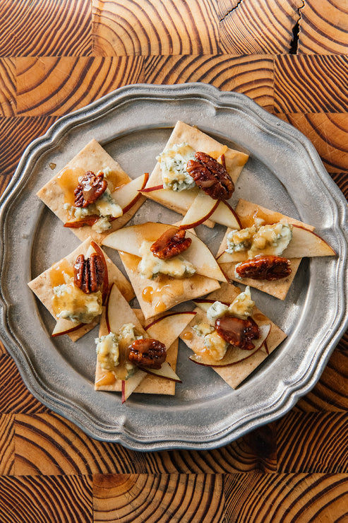 Load image into Gallery viewer, Silver platter of crackers topped with blue cheese, apples, and Candied Pecans on a wooden surface
