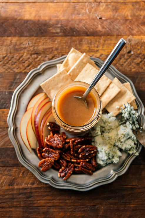 Load image into Gallery viewer, American Spoon Cinnamon Honey and Candied Pecans on a Platter with assorted cheeses, crackers and apple slices on a textured surface
