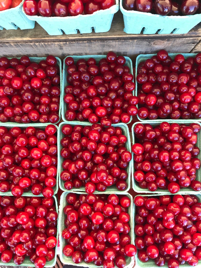 Turquoise quart boxes filled with bright red sour cherries.