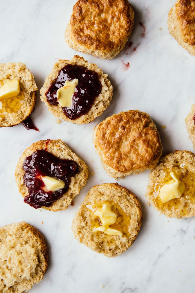 Open face homemade biscuits with preserves and melted butter.