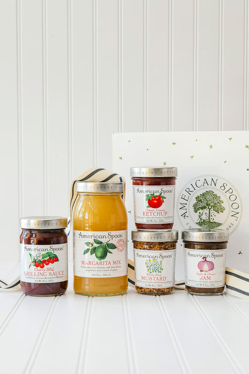 Load image into Gallery viewer, the backyard bbq gift box including cherry bbq grilling sauce, classic tomato ketchup, whole seed mustard, apple &amp; onion jam and margarita mix in front of an american spoon gift box and ribbon
