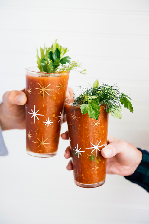 Load image into Gallery viewer, Two glasses of Bloody Mary cokctails topped with celery and herbs in a cheers

