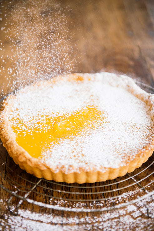 Load image into Gallery viewer, A homemade lemon curd tart sprinkled with powdered sugar
