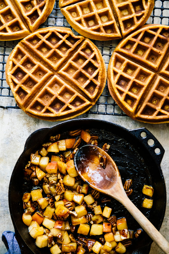Waffles with sauteed apples and pecans in a skillet