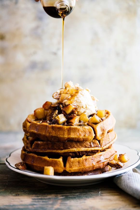 A stack of waffles with sauteed apples, ice cream and Maple Syrup