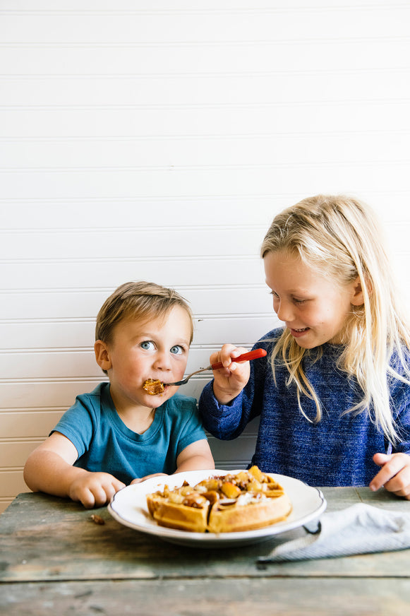 A young boy and girl eating a waffle