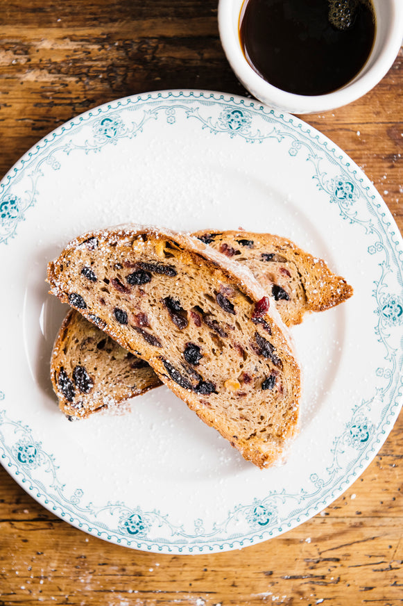 Two slices of Midwest Stollen on a plate with coffee next to it