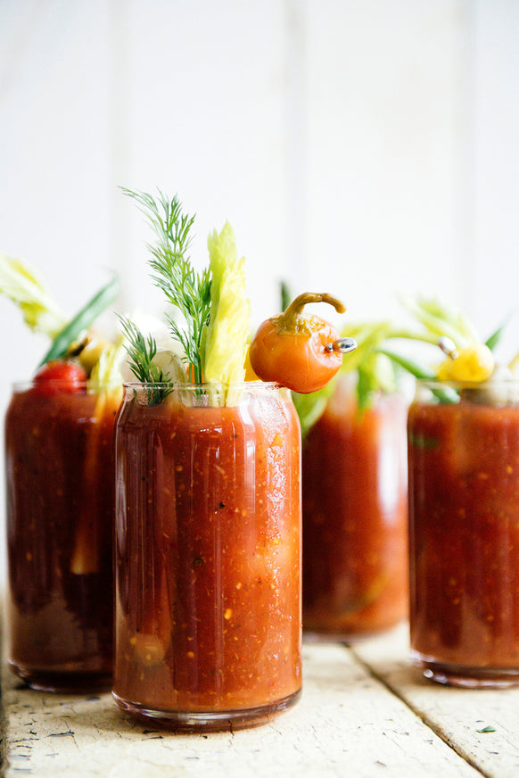 Glasses of Bloody Mary's topped with celery, herbs and peppers
