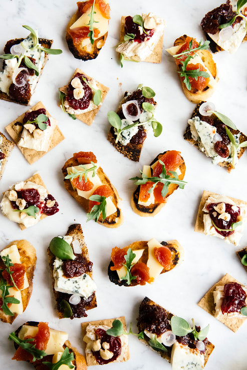 Load image into Gallery viewer, Crackers topped with arugula, blue cheese and preserves
