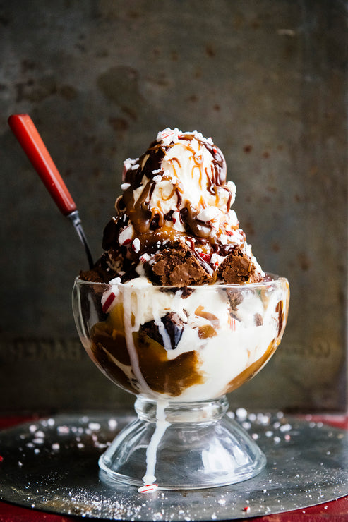 Load image into Gallery viewer, An ice cream and brownie sundae topped with peppermint pieces, caramel and Chocolate Fudge Sauce
