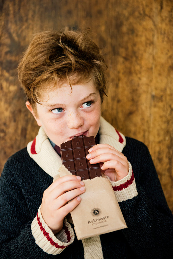 A young boy eating aDark Chocolate & Raspberry Askinosie Chocolate Bar