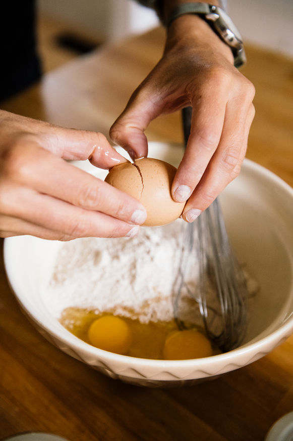 Cracking eggs over a bowl of pancake mix