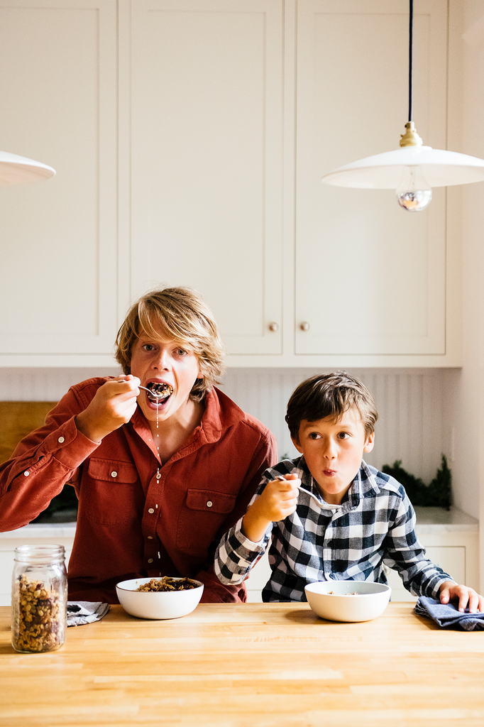 Two young boys, eating Maple Granola by the spoonful with milk