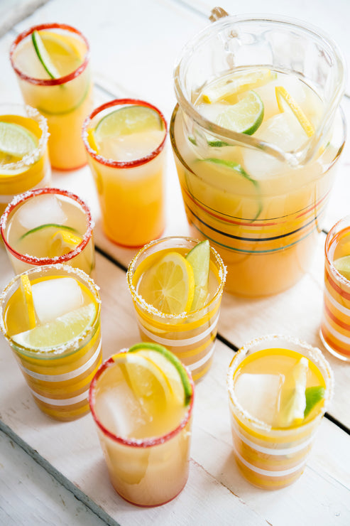 Load image into Gallery viewer, Pitcher of Margarita Mix with fresh lime and lemon slices poured into individual cups
