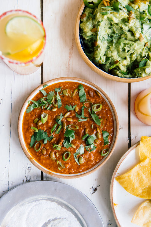 Load image into Gallery viewer, Pumpkin Seed Salsa topped with cilantro and green onions, fresh guacamole and tortilla chips with a glass of Margarita Mix
