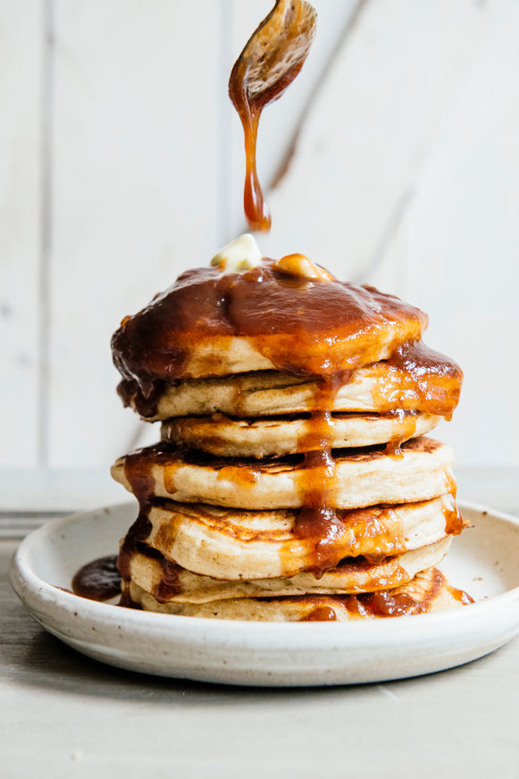 A stack of Pancakes topped with butter, Maple Pumpkin Caramel and Apple Butter