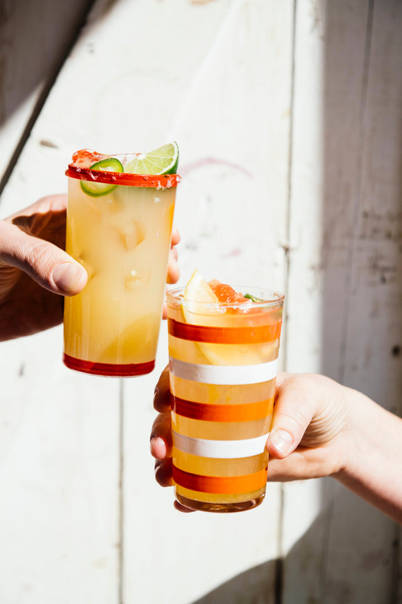 Two glasses of Margarita Mix with fresh fruit being clinked together