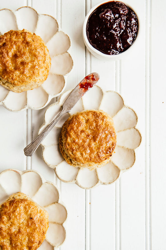 Three homemade biscuits on separate plates with preserves
