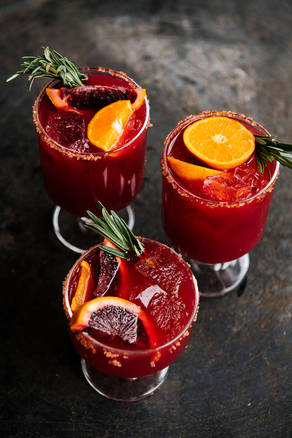 Cocktails in individual glasses made with Holiday Punch and fresh fruit