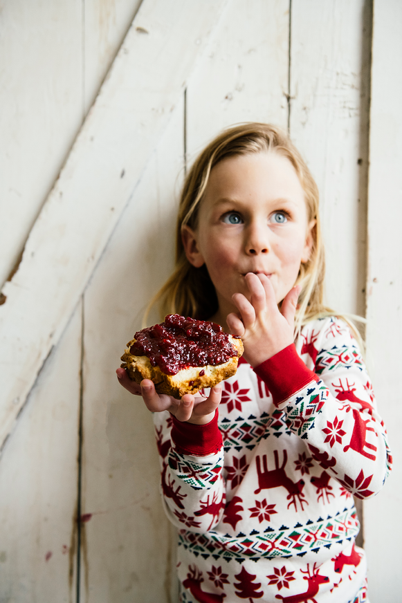 A young girl holding a piece of toast covered in preserves