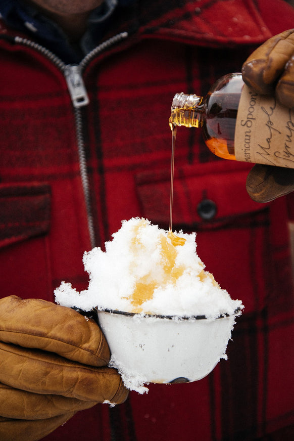 A cup of snow with Maple Syrup being drizzled on top