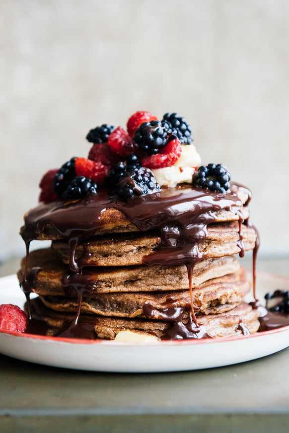 Stack of chocolate pancakes topped with Chocolate Fudge Sauce and fresh fruit